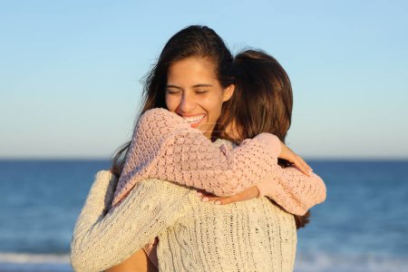 Foto de Dos amigos felices conociéndose y abrazándose en la playa al atardecer - Imagen libre de derechos