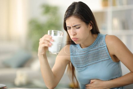 Foto de Mujer que sufre dolor de vientre beber leche en casa - Imagen libre de derechos