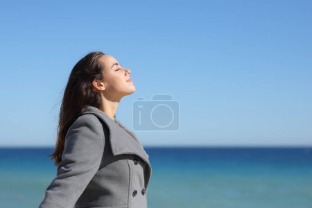 Foto de Retrato de una mujer relajada en invierno respirando aire fresco en la playa - Imagen libre de derechos