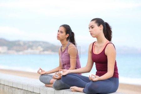 Foto de Dos yoguis aburridos haciendo ejercicios de yoga en la playa - Imagen libre de derechos