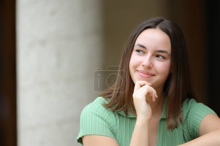 Photo for Front view portrait of a satisfied woman wondering looking at side outdoors in the street - Royalty Free Image