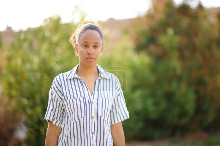 Téléchargez les photos : Femme noire sérieuse vous regardant dans un parc - en image libre de droit