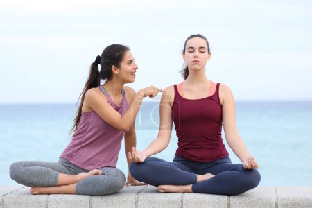 Téléchargez les photos : Femme faisant du yoga ignorant son ami ennuyeux sur la plage - en image libre de droit