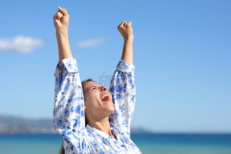 Photo for Excited woman raising arms on the beach celebrating success - Royalty Free Image