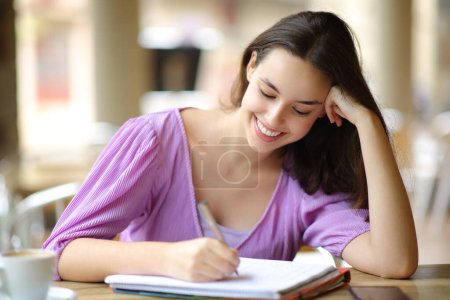 Heureux étudiant prenant des notes dans une terrasse de café