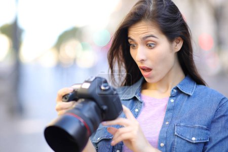 Téléchargez les photos : Photographe surpris de vérifier les photos sur l'appareil photo dans la rue - en image libre de droit