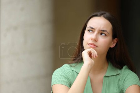 Photo for Front view portrait of a pensive woman looking at side planning in the street - Royalty Free Image