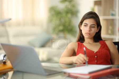 Foto de Estudiante distraído esperando mirando el portátil en casa - Imagen libre de derechos