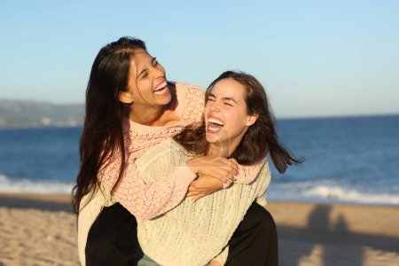 Photo for Two joyful friends joking and laughing hilariously on the beach at sunset - Royalty Free Image