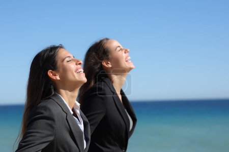 Téléchargez les photos : Profil de deux cadres heureux qui respirent l'air frais sur la plage - en image libre de droit
