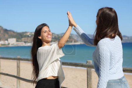 Téléchargez les photos : Deux femmes heureuses se rencontrent et donnent cinq sur la plage - en image libre de droit