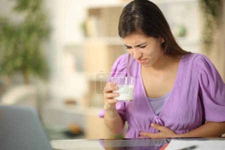 Foto de Lactosa intolerante mujer bebiendo leche sufriendo dolor de vientre en casa - Imagen libre de derechos