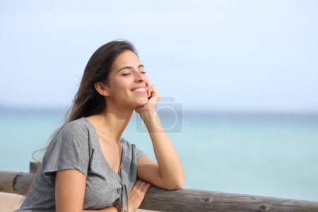 Téléchargez les photos : Femme heureuse avec les yeux fermés se reposant profiter d'une journée ensoleillée sur la plage - en image libre de droit