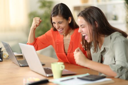 Foto de Dos teletrabajadores emocionados celebrando el éxito en línea comprobación portátil en casa - Imagen libre de derechos