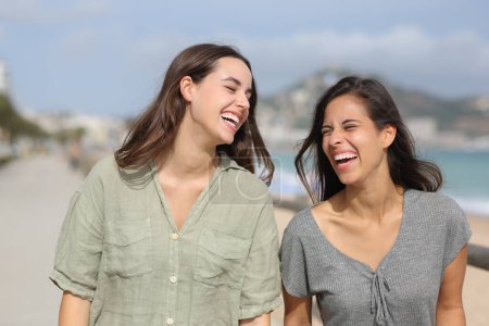 Foto de Retrato de dos amigos alegres caminando y riendo en la playa - Imagen libre de derechos
