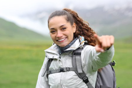 Téléchargez les photos : Joyeux randonneur pointant vers la caméra dans la montagne - en image libre de droit