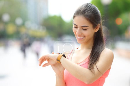 Foto de Feliz corredor comprobar el tiempo en smartwatch después de correr en la calle - Imagen libre de derechos