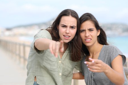 Upset women pointing at you accusing on the beach