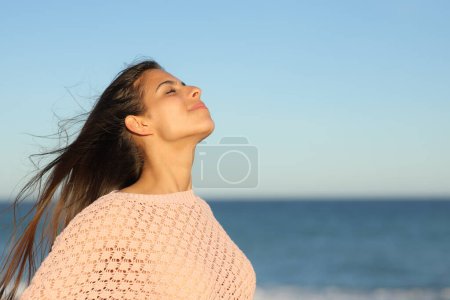 Téléchargez les photos : Femme au coucher du soleil respirant l'air frais sur la plage - en image libre de droit