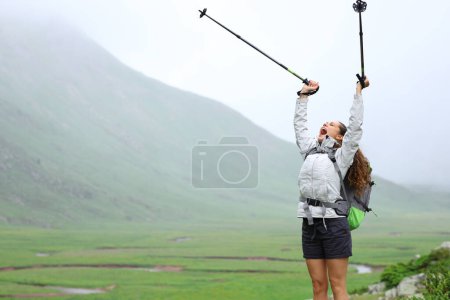 Téléchargez les photos : Randonneur passionné levant des bâtons célébrant des vacances en montagne - en image libre de droit