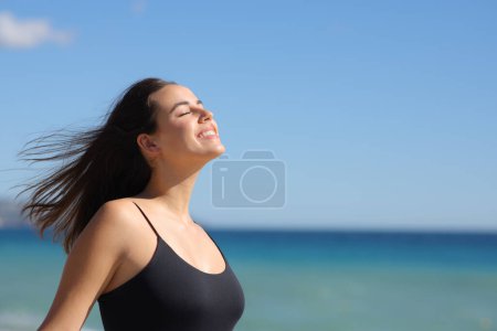 Téléchargez les photos : Happy casual femme respirant de l'air frais sur la plage une journée ensoleillée d'été - en image libre de droit