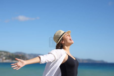 Téléchargez les photos : Profil d'une femme excitée bras tendus sur la plage - en image libre de droit