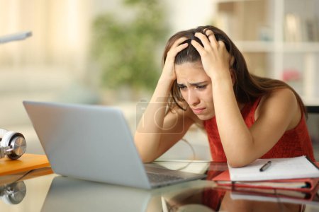 Téléchargez les photos : Triste étudiant vérifier ordinateur portable essayant d'apprendre la leçon en ligne à la maison - en image libre de droit