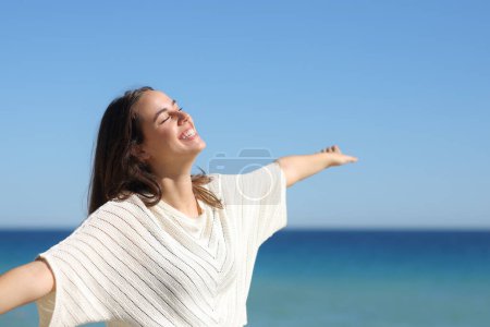 Foto de Mujer feliz celebrando un buen día extendiendo los brazos en la playa - Imagen libre de derechos