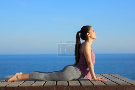 Foto de Perfil de un yogui haciendo ejercicio de yoga en la costa - Imagen libre de derechos