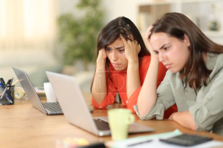 Worried tele workers checking bad news on computer at home
