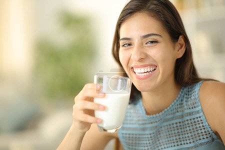 Téléchargez les photos : Femme heureuse riant et posant tenant verre de lait à la maison - en image libre de droit