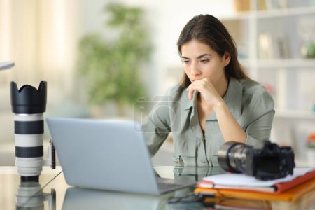 Photo for Worried photographer working checking laptop sitting at home - Royalty Free Image
