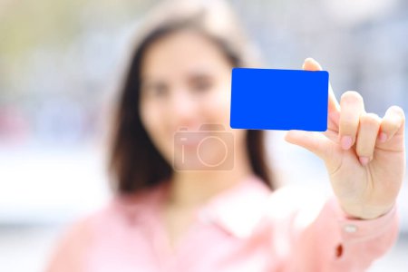 Téléchargez les photos : Portrait en gros plan d'une élégante main de femme montrant une maquette de carte de crédit noire dans la rue - en image libre de droit