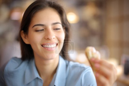 Femme heureuse avec le sourire blanc et les lèvres sales de sucre regardant croissant dans un restaurant