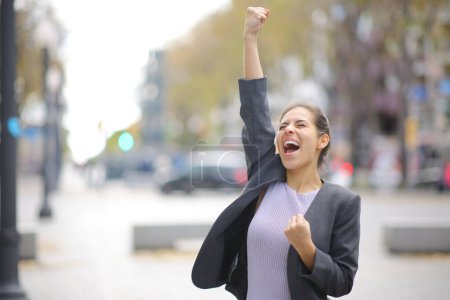 Foto de Emocionada empresaria celebrando en la calle levantando el brazo y gritando - Imagen libre de derechos