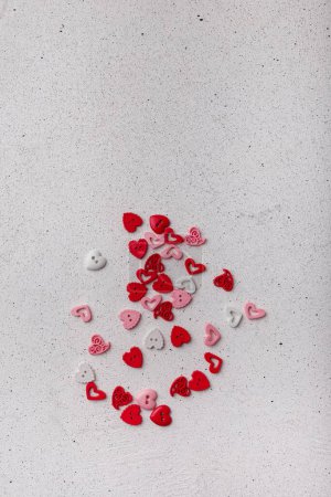 Photo for Heap of red pink and white decorative heart-shaped buttons on white background. Ornamental details for sewing, scrapbooking, handmade - Royalty Free Image