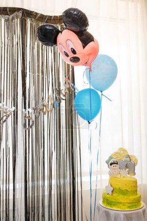 Téléchargez les photos : Izmail, Ukraine. May 2022. One year old baby boy birthday cake with toppers and number 1 gingerbread cookie. Blue balloons and Mickey Mouse head balloon - en image libre de droit