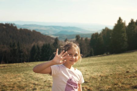 Girl outdoors in the mountains in summer. Communication between a child and nature. Unity with the outside world