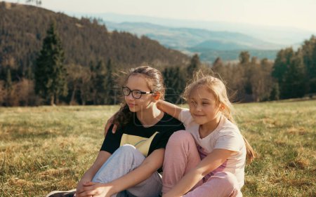 Two girls in nature in the mountains laugh merrily and have a great time together. Friendship and fun