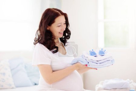 Photo for Pregnant woman at home. Young expecting mother in white bedroom. Healthy pregnancy. Female looking at baby sonogram preparing for birth. Maternity and prenatal care. - Royalty Free Image