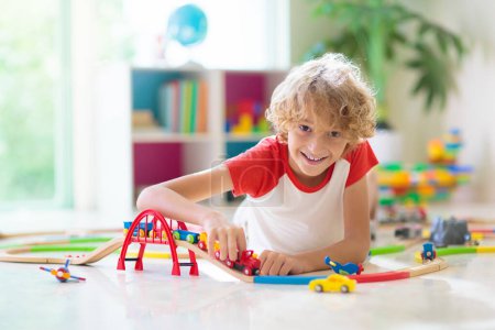 Photo for Kids play with toy train railway. Child playing with colorful rainbow wooden trains. Toys for little boy. Preschooler building rail road at home or daycare, preschool. Kindergarten educational games. - Royalty Free Image