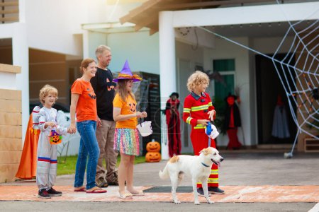Photo for Kids trick or treat on Halloween night. Dressed up children at decorated house door. Boy and girl in witch and vampire costume and hat with candy bucket and pumpkin lantern. Autumn home decoration. - Royalty Free Image