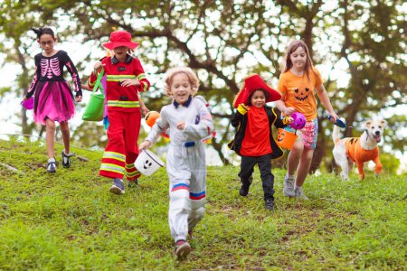 Photo for Child in Halloween costume. Mixed race kids and parents trick or treat on street. Little boy and girl with pumpkin lantern and candy bucket. Baby in witch hat. Autumn holiday fun. - Royalty Free Image