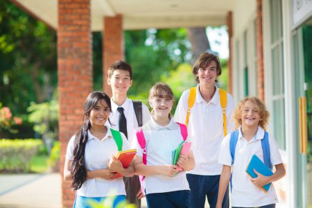 Photo for Kids go back to school. Interracial group of children of mixed age on the first day of new academic year. Teenager in classroom. High and middle school students walk to lesson. Secondary student class - Royalty Free Image