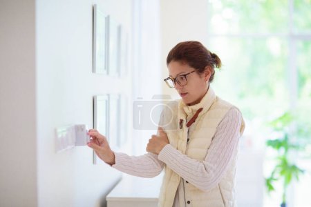 Woman adjusting thermostat. Central heating. Comfortable home temperature. Female setting room climate control regulator. Heating on cold winter day in freezing house. Indoor split air conditioning.