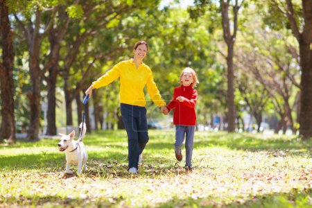 Photo for Family walking in autumn park. Kids play in sunny forest. Outdoor fun. Mother, father and children walk the dog on sunny warm fall day. Boy and girl in rain jacket. Parents with son and daughter. - Royalty Free Image