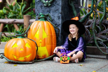 Photo for Child in Halloween costume. Kids trick or treat. Little girl dressed as witch with hat holding pumpkin lantern and candy bucket. Family celebration. - Royalty Free Image