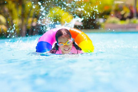 Photo for Child in swimming pool floating on toy ring. Kids swim. Colorful rainbow float for young kids. Little boy having fun on family summer vacation in tropical resort. Beach and water toys. Sun protection. - Royalty Free Image