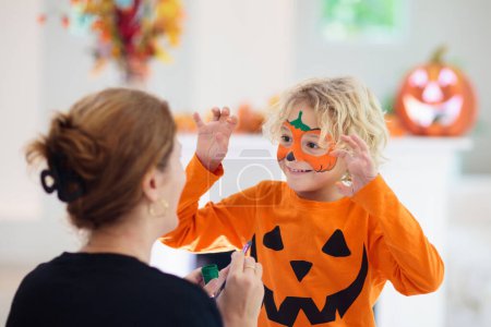 Photo for Child and mother in Halloween costume. Kids trick or treat. Face painting for party event. Little boy dressed as evil vampire with pumpkin lantern. Family celebration. Mom and son with candy. - Royalty Free Image