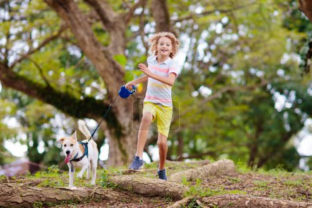 Photo for Child and dog walk in summer park. Little boy playing with his puppy. Family walking dog. Kids and pets friendship. Animal love and care. Children and pets. - Royalty Free Image